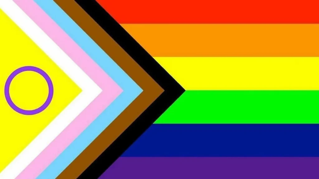 Progress Pride flag with intersex symbol: yellow triangle with purple circle and rainbow stripes.